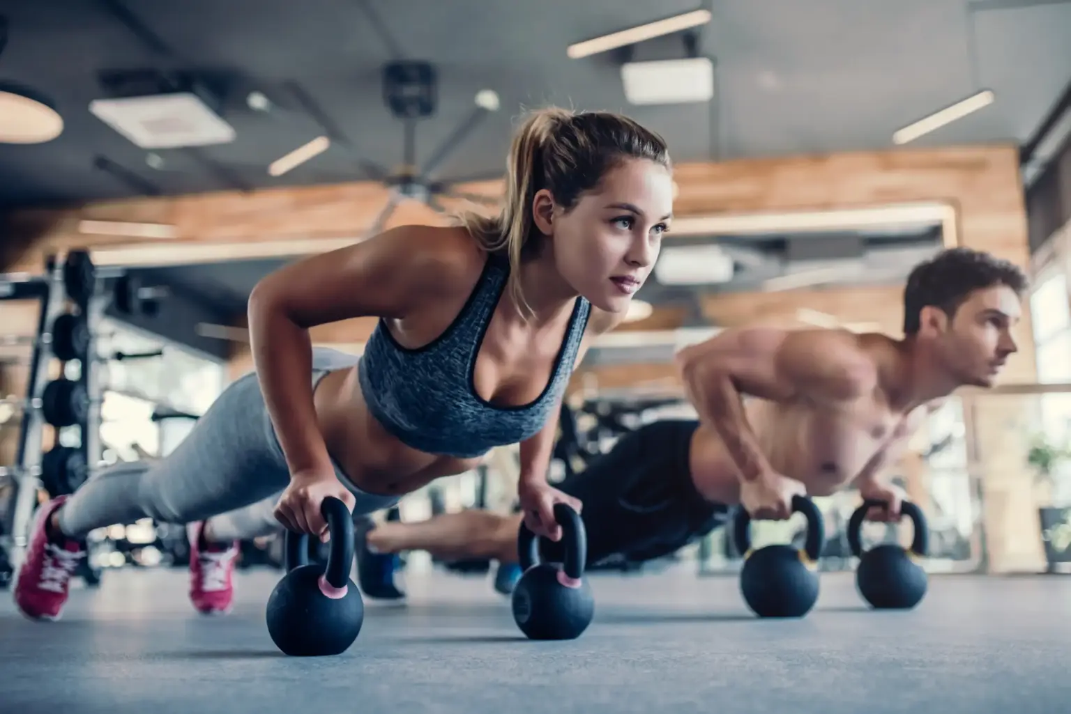 Two athletes training with kettlebells in a gym as part of a fitness routine supported by fitness supplements in South Africa